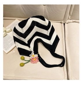 Detail of hand-woven black and white wave pattern tote bag with 3D floral charm