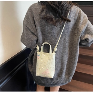 Détail du sac cabas brodé avec motifs fleurs et papillons porté par un mannequin