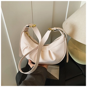 Détails de la texture grainée du sac demi-lune beige clair avec boucles dorées