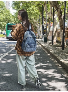 Macro detail of retro denim backpack with ethnic patterned straps shown on model