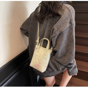 Détail de la broderie florale et du papillon sur un sac fourre-tout beige chic