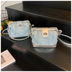 Close-up of light blue quilted denim mini crossbody bags with silver chain straps