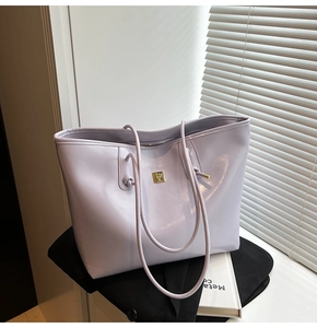 Close-up of lavender tote bag with golden metal plate on a black blazer backdrop