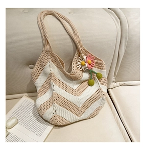 Macro detail of hand-woven crochet shoulder bag with floral pendant on a cream sofa