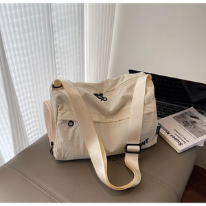 Detail of off-white nylon travel bag with adjustable strap and side zipper pocket