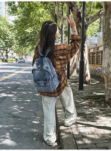 Outdoor view of a model wearing a retro washed denim backpack in dark blue finish
