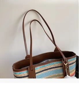 Détail du sac cabas tissé multicolore avec poignées en cuir marron et anneaux métalliques