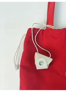 Detail of red canvas tote bag with white leather pendant and silver metal ring buckle