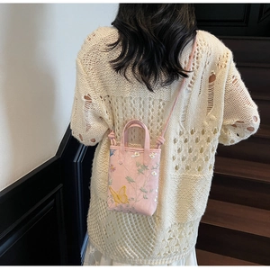 Détail de broderie fleurs et papillon sur un petit sac à bandoulière en toile rose