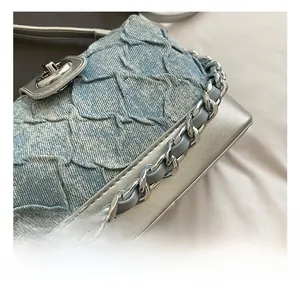 Detail of light blue denim waffle texture with silver metallic leather and chain strap