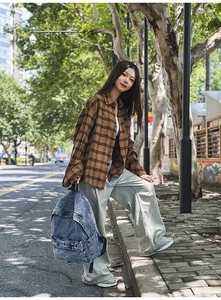 Detail of vintage denim backpack paired with a brown plaid shirt and wide leg jeans