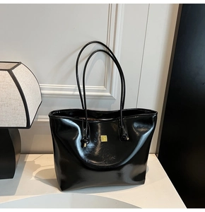 Detail of high-gloss black oil wax leather tote bag with square gold metal buckle