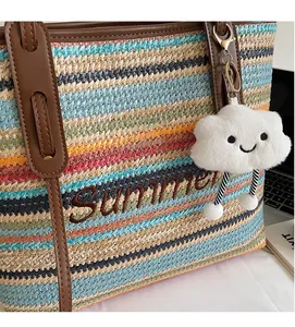 Détail d'un sac cabas en paille rayé avec broderie Summer et breloque nuage