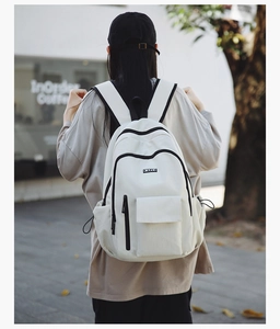 Outdoor shot of a beige canvas backpack featuring black zippers and a flap front pocket