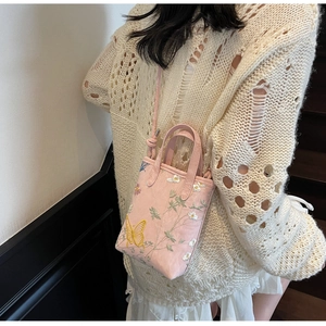 Détail de la broderie papillon rose sur un sac cabas avec des accents floraux