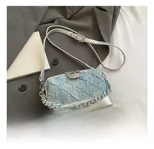 Detail view of silver chain and blue textured fabric on a stylish crossbody bag