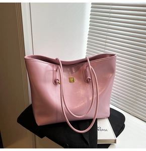 Detail view of pink glossy tote bag featuring golden square logo and zip closure