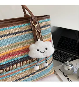 Détail d'un charme nuage en peluche avec smiley sur un sac fourre-tout tissé d'été