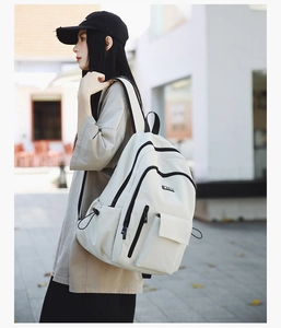 Side view of cream large capacity backpack with black zippers worn on street