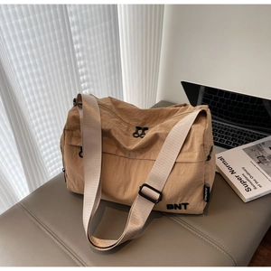 Detail of khaki nylon shoulder bag featuring an adjustable strap and BNT logo print