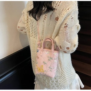 Détail du mini sac rose avec broderies fleurs et papillons sur tissu en suédine