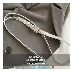 Macro detail of adjustable light gray leather strap with silver pin buckle and stitching