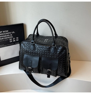 Detail of woven black travel bag featuring dual front pockets with silver metal buckles