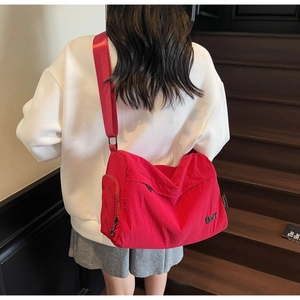 Detail of red nylon crossbody bag featuring BNT embroidery and functional mesh pocket