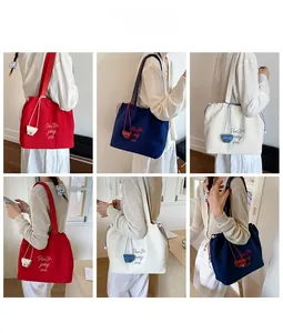 Detail view of canvas tote bag with drawstring closure and letter embroidery in three colors