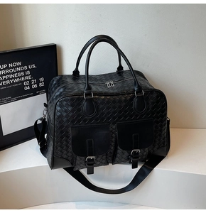 Detailed view of black woven travel bag featuring front flap pockets and metallic buckles