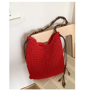 Detail of red crochet tote bag featuring handcrafted knit texture and wooden bead strap