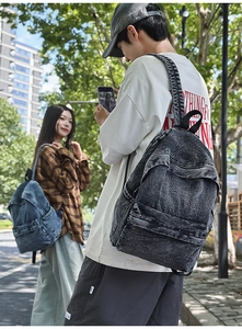 Detailed view of washed denim backpacks in dark gray and blue shown in outdoor lifestyle scene