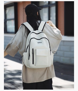 Outdoor shot showing back view of large capacity cream backpack with black zippers