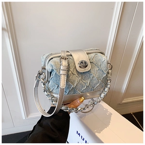 Detail of light blue denim crossbody bag with silver chain and textured pleats