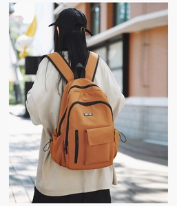 Outdoor street shot of a mustard yellow backpack featuring multi-pocket storage and black zippers