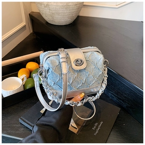 Detail of light blue denim crossbody bag featuring silver metal clasp and chain strap