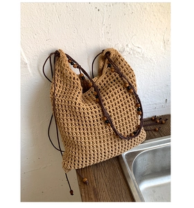 Detail of woven straw bucket bag showing hollow crochet texture and wooden bead handle