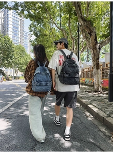 Outdoor street scene showcasing blue and dark grey denim backpacks for couples or students