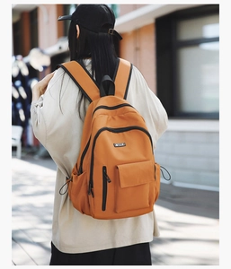Outdoor shot of bright orange waterproof backpack with multi-pockets and black zippers