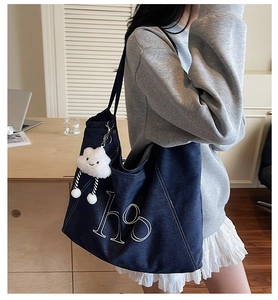 Detail of dark blue denim tote bag with white embroidery and cute cloud pendant