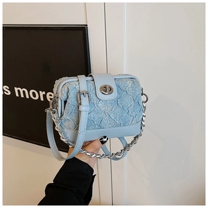 Close-up of light blue pleated fabric crossbody bag with silver twist lock and chain