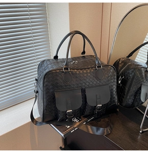 Close-up of woven texture black travel bag with dual front pockets and adjustable strap