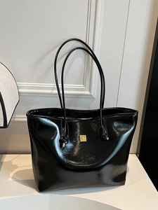 Minimalist black patent leather tote bag with gold metal logo for daily commute