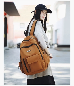 Detailed view of brown travel backpack with zipper compartments on casual outdoor model