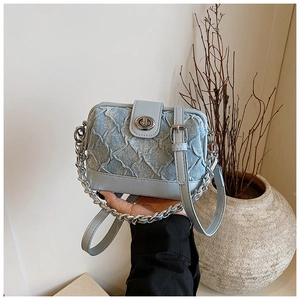 Detail of light blue denim and leather bag with quilted pattern and silver chain strap
