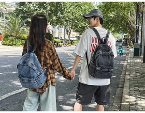 Outdoor shot of models wearing vintage denim backpacks in blue and charcoal grey colors