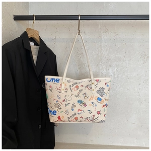 Detail of large beige tote bag with colorful cartoon graffiti and long shoulder straps