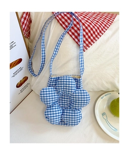 Dettaglio della borsa a tracolla a fiori a quadretti bianchi e blu su un tavolo decorato