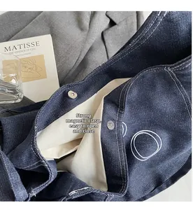 Detail view of denim tote bag showing secure magnetic buckle and canvas lining interior