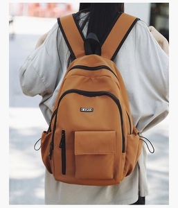 Detailed view of the dark caramel backpack with multi-compartments on a person outdoors